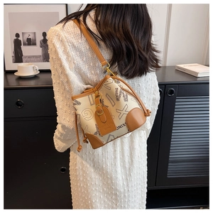 Détail du sac seau en toile avec finitions en cuir marron, imprimés et cordon de serrage