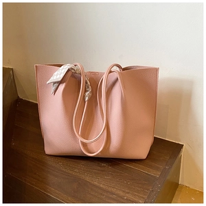Detail of pink pebbled leather tote bag with elegant checkered scarf wrapped on the handle
