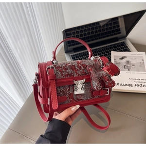 Detail of red leather crossbody bag with silver phoenix embroidery and bird-shaped buckle