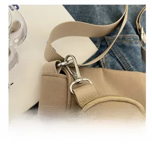 Détail du crochet métallique argenté et de la bandoulière d'un sac fourre-tout en nylon beige