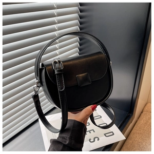 Close-up of black saddle bag featuring smooth faux leather finish and a stylish square buckle