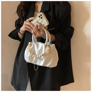 Detail of white pleated cloud bag showing soft leather texture and stylish bead chain