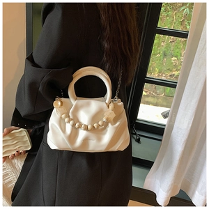 Detailed side view of white pleated cloud bag with pearl handle and metal chain strap