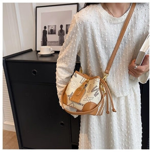 Détail du sac seau avec motifs de lettres et garniture en cuir marron élégant