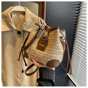 Detail view of woven straw bucket bag with brown leather trim and drawstring closure