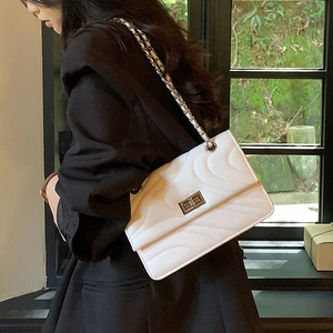 Sac à bandoulière matelassé blanc élégant avec chaîne en métal porté par un mannequin