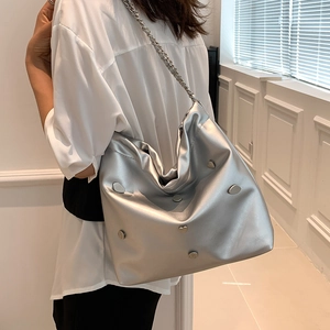 Chic silver metallic chain bucket bag with heart charms shown on a casual female model