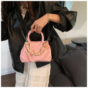 Detail of a pink pleated cloud bag featuring marble bead chain and metal shoulder strap