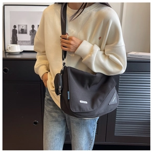 Détail d'un grand sac bandoulière en nylon noir avec sangle ajustable et porte-monnaie assorti