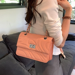 Sac bandoulière matelassé rose orangé avec coutures vagues et fermoir rotatif argent