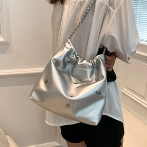 Silver metallic chain bucket bag with heart studs on a model in a minimalist setting