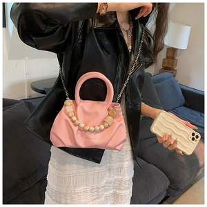 Close-up of pink ruched cloud bag featuring decorative pearl handle and silver chain strap