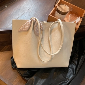 Minimalist beige tote bag with litchi texture and silk scarf shown on a warm background