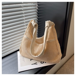 Detailed close-up of the hollow woven texture and knot handle on this beige straw bag