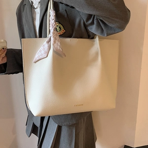 Minimalist beige pebble leather tote bag with a decorative silk scarf for daily commute