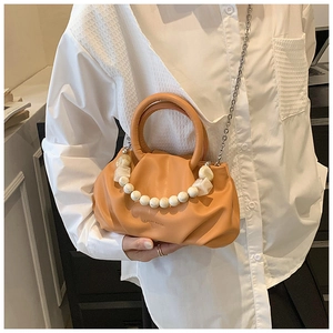 Detail of orange pleated cloud bag with marble bead handle and metal crossbody chain