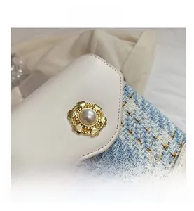 Close-up of blue tweed cross-body bag with golden pearl clasp and leather flap