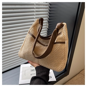 Detailed close-up of beige straw tote bag with brown leather handles and knotted detail