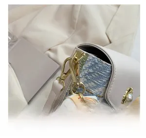 Detail of tweed crossbody bag featuring gold hardware and silk scarf decoration