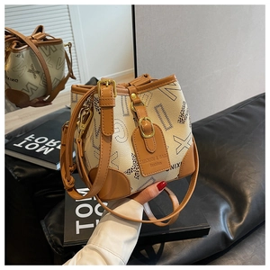 Détail du sac seau crème avec bordure en cuir marron et bandoulière ajustable