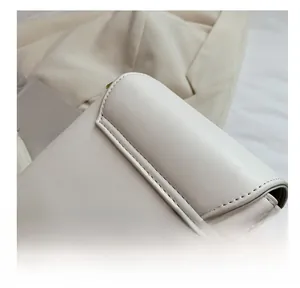 Detail shot of precise stitching on cream-white leather small square shoulder bag