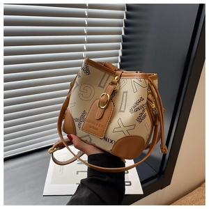 Détail du sac seau léopard avec garniture en cuir marron et finitions dorées