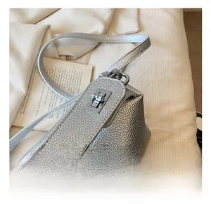 Détail d'un sac à main argenté texture litchi avec un fermoir tournant en métal chic