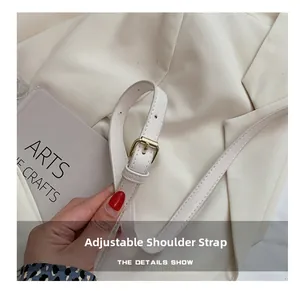 Detail of adjustable white leather strap with gold buckle on a stylish crossbody bag