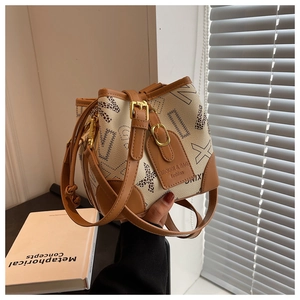 Détail du sac seau crème avec imprimés de lettres, motifs léopard et bandoulière en cuir