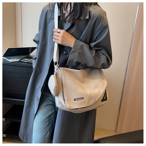 Détail d'un grand sac bandoulière blanc cassé avec un porte-monnaie rond assorti