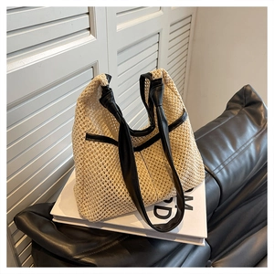 Detailed shot of beige woven tote bag with black leather handles on minimalist background