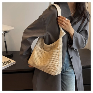 Detail of hand-woven straw shoulder bag featuring white leather knotted straps and front pocket