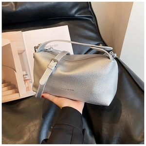 Détail du sac polochon argenté en cuir grainé avec texte Fashion & Bags sur la surface