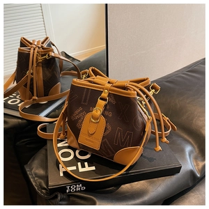 Détail d'un sac seau monogramme marron avec fermeture à cordon et boucles dorées