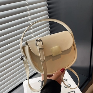 Minimalist beige leather saddle handbag with curved handle and adjustable strap for women