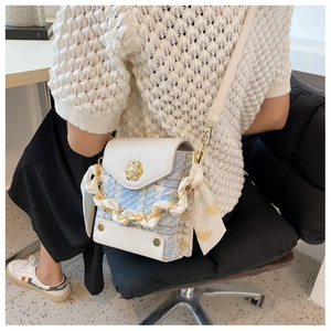 Detail of tweed crossbody bag with gold pearl buckle and silk scarf wrapped chain handle