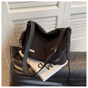 Détail du sac bandoulière en nylon noir avec sangle réglable et petite pochette