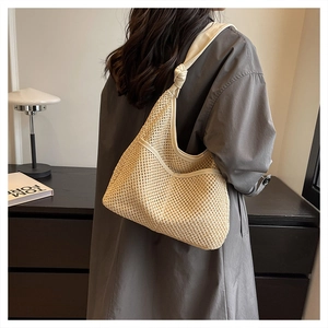 Detail of hand-woven straw hobo bag with cream leather trim and stylish knotted shoulder strap