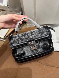 Close-up of black crossbody bag with white flower embroidery and silver metal clasp