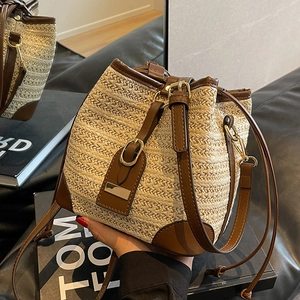 Woven straw bucket bag with brown leather trim and drawstring for a casual summer look