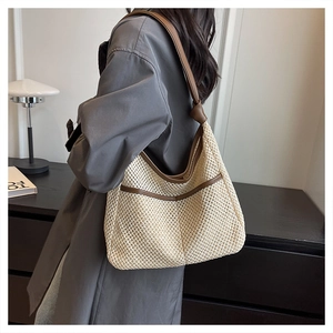 Detail of hand-woven straw tote bag with brown leather trim and knotted shoulder strap