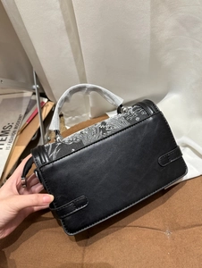 Detailed close-up of a black leather handbag featuring a stylish white wave pattern design