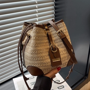 Minimalist woven straw bucket bag with brown leather trim and golden metal hardware