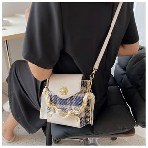 Detail of tweed crossbody bag with pearl buckle and silk scarf chain on model