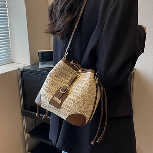 Chic woven straw bucket bag with brown leather trim and metallic buckle detail for summer