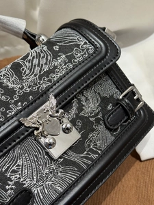 Detail of elegant black jacquard handbag featuring a silver Pegasus shield buckle