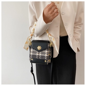 Detail of tweed crossbody bag featuring pearl gold buckle and silk scarf woven chain strap