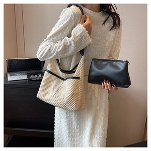 Detail view of woven straw tote bag with black leather trim and matching zip pouch