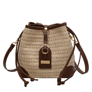 Summer woven straw bucket bag with brown leather trim and metallic gold buckle details