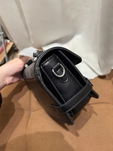 Detail of black leather texture and silver D-ring buckle on a stylish mini handbag